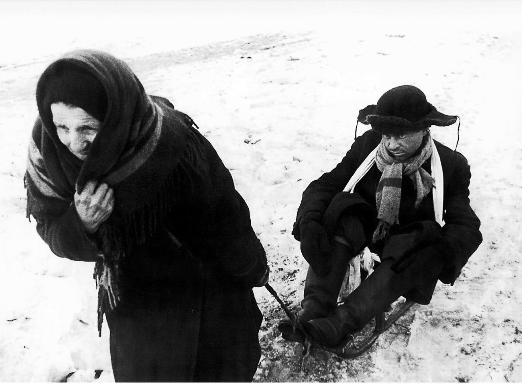 1942,7 февраля. Пожилая ленинградка везет на санках мужчину-дистрофика.