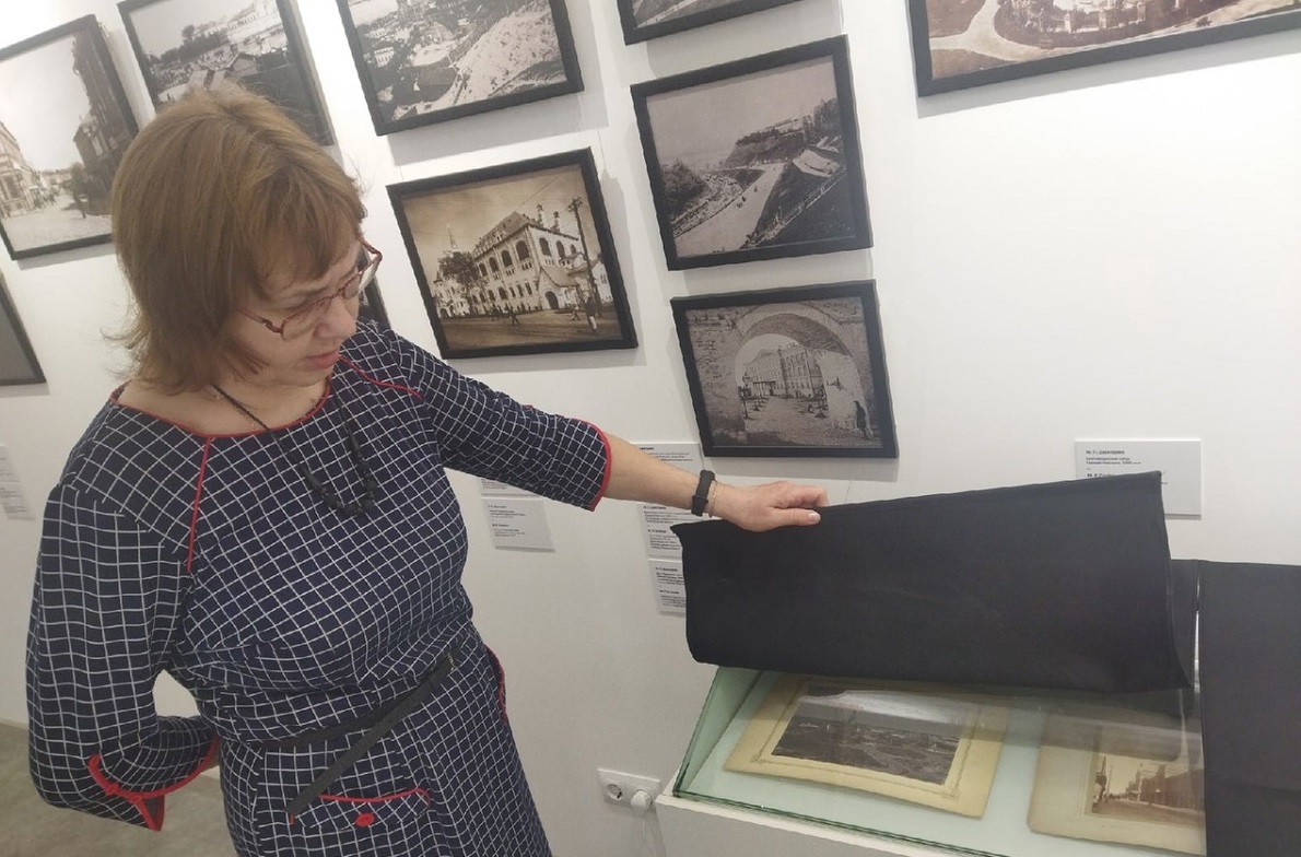 Директор музея показывает подлинники дореволюционных фото Нижнего, защищенных от света черной тканью