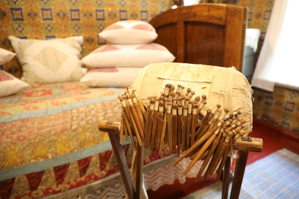 Валик и коклюшки для плетения кружев в комнате бабушки