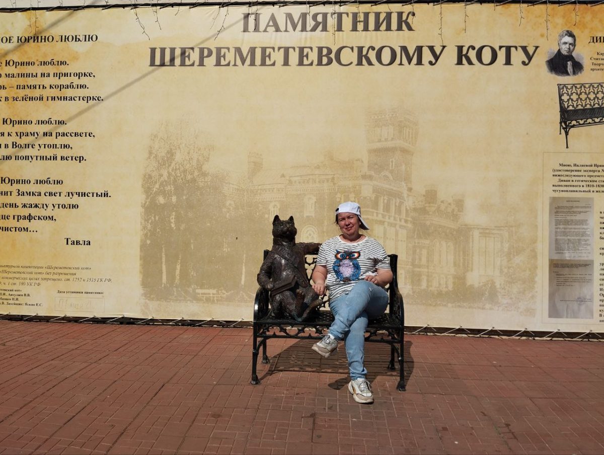 Под часами сидит на скамье Шереметевский кот с книжкой в лапах. Приглашает присесть рядом с ним на скамейку и сделать отличное фото на память